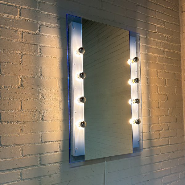 FLiRD maatwerk spiegellamp met spiegel en acht E14 LED kopspiegellampen gemonteerd aan de wand in een hotelkamer.